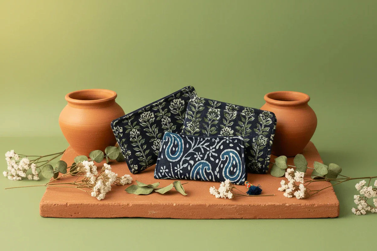 Three Indian handmade block-print cotton long wallets with clay pots and dried wildflowers on terracotta — Velunora Handmade Wallets Collection